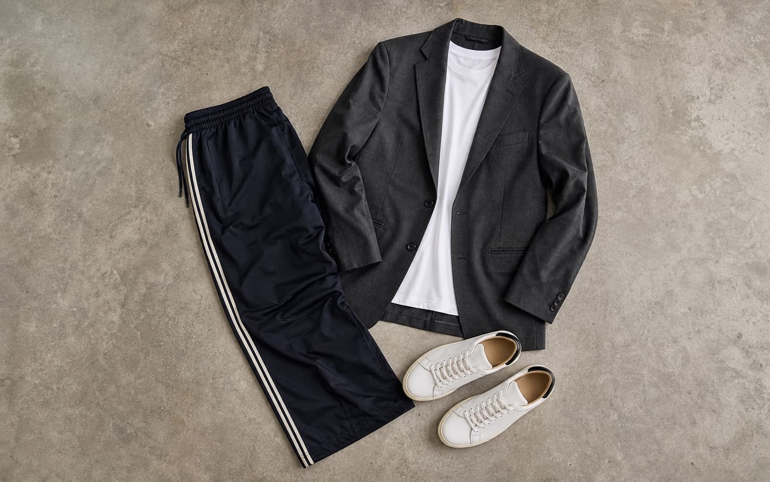 Track pants, a plain tee, relaxed blazer, and leather sneakers arranged as a sport-meets-tailoring outfit.