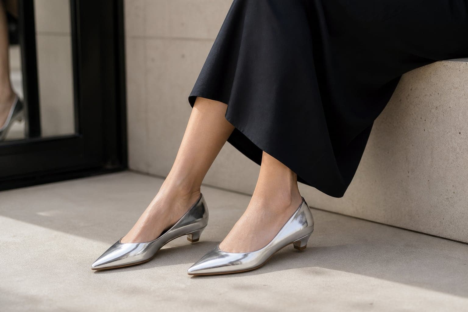 Silver metallic pointed flats worn with a simple dark outfit.