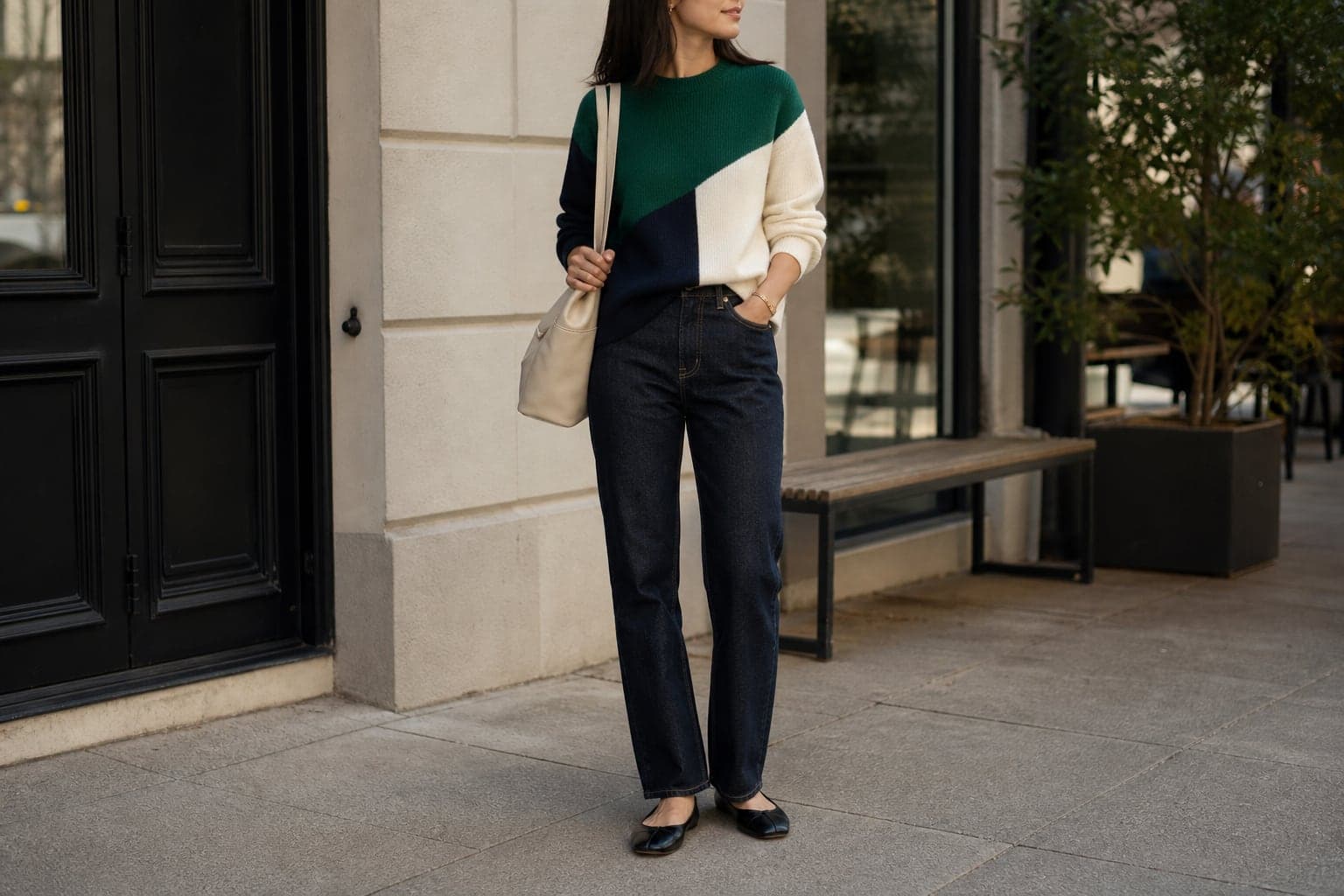 A color-blocked knit with dark denim, simple flats, and a neutral bag.