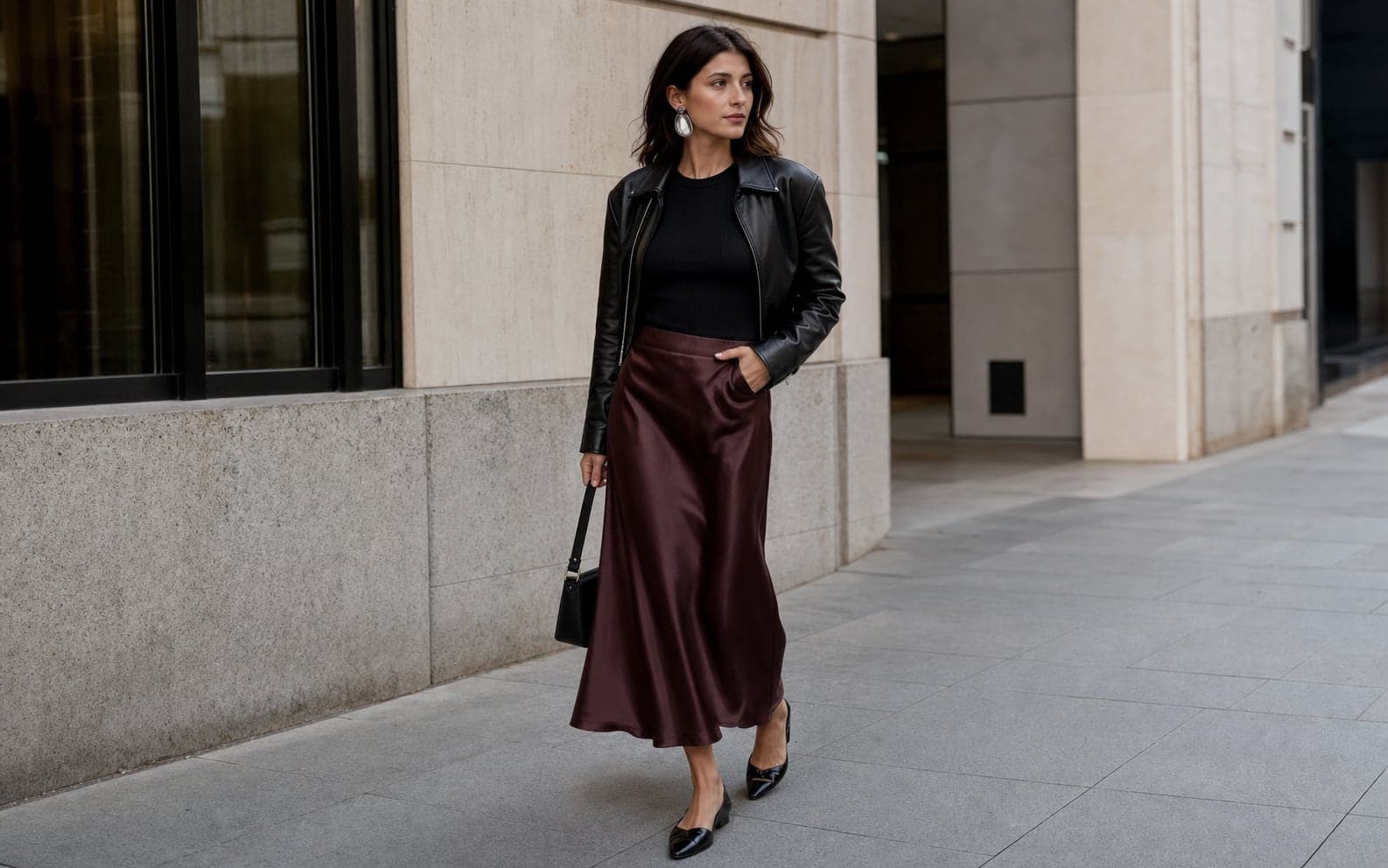 A woman wearing fluid charcoal wide-leg trousers with a fitted black knit shell and loafers.