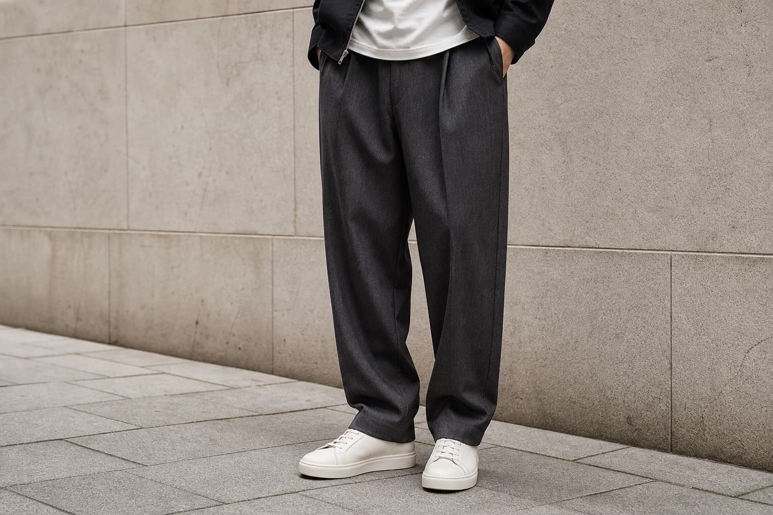 Relaxed charcoal pleated trousers with off-white leather sneakers.