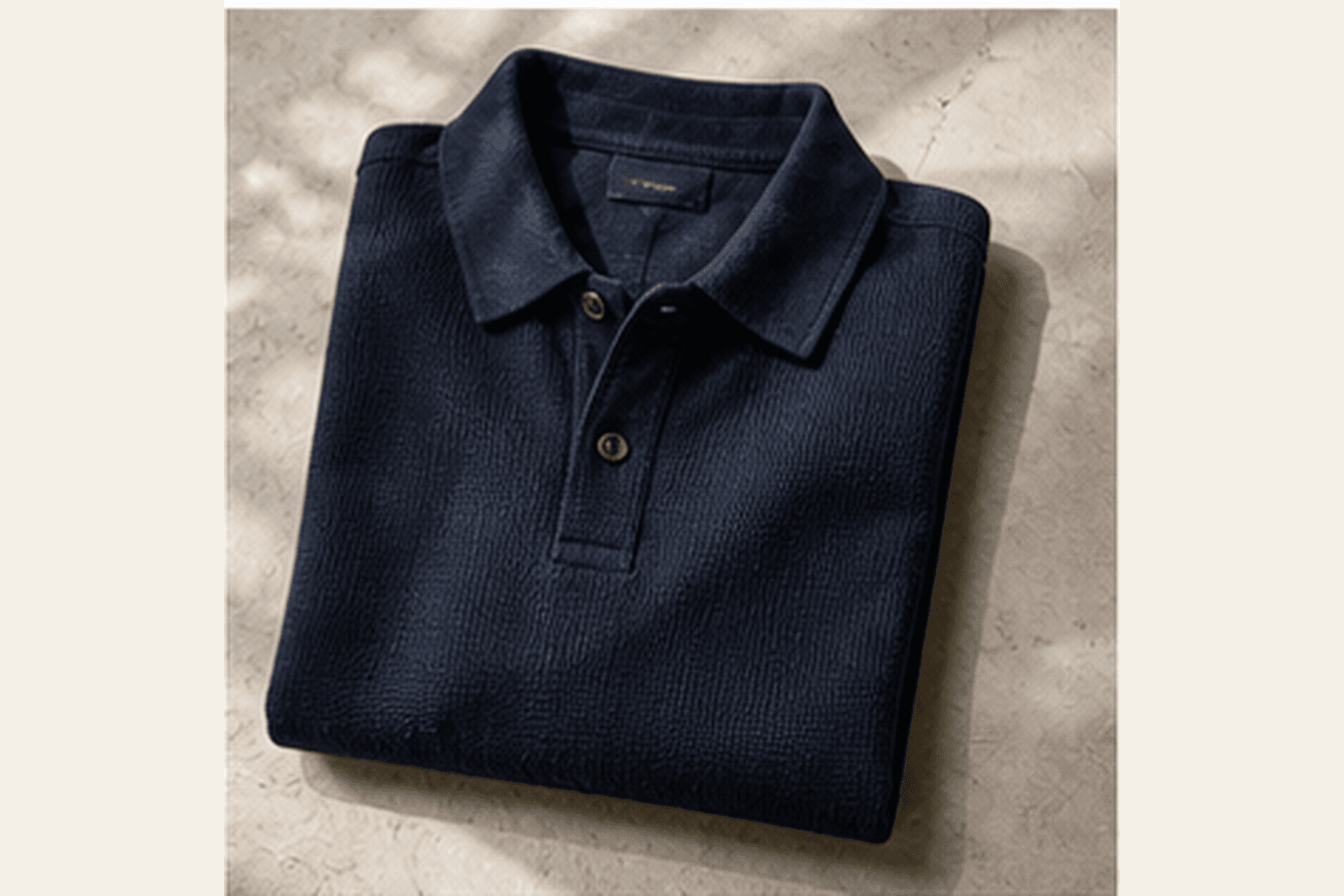 Folded navy knit polo shirt on a neutral studio surface.
