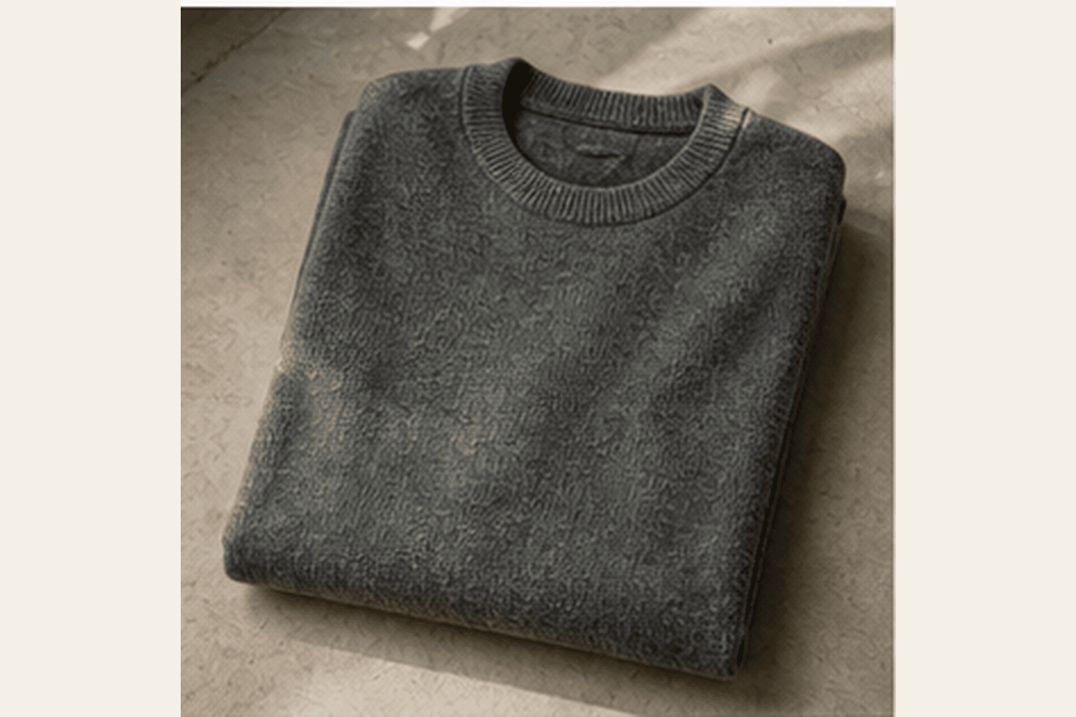 Folded charcoal fine-gauge crewneck sweater showing soft knit texture.
