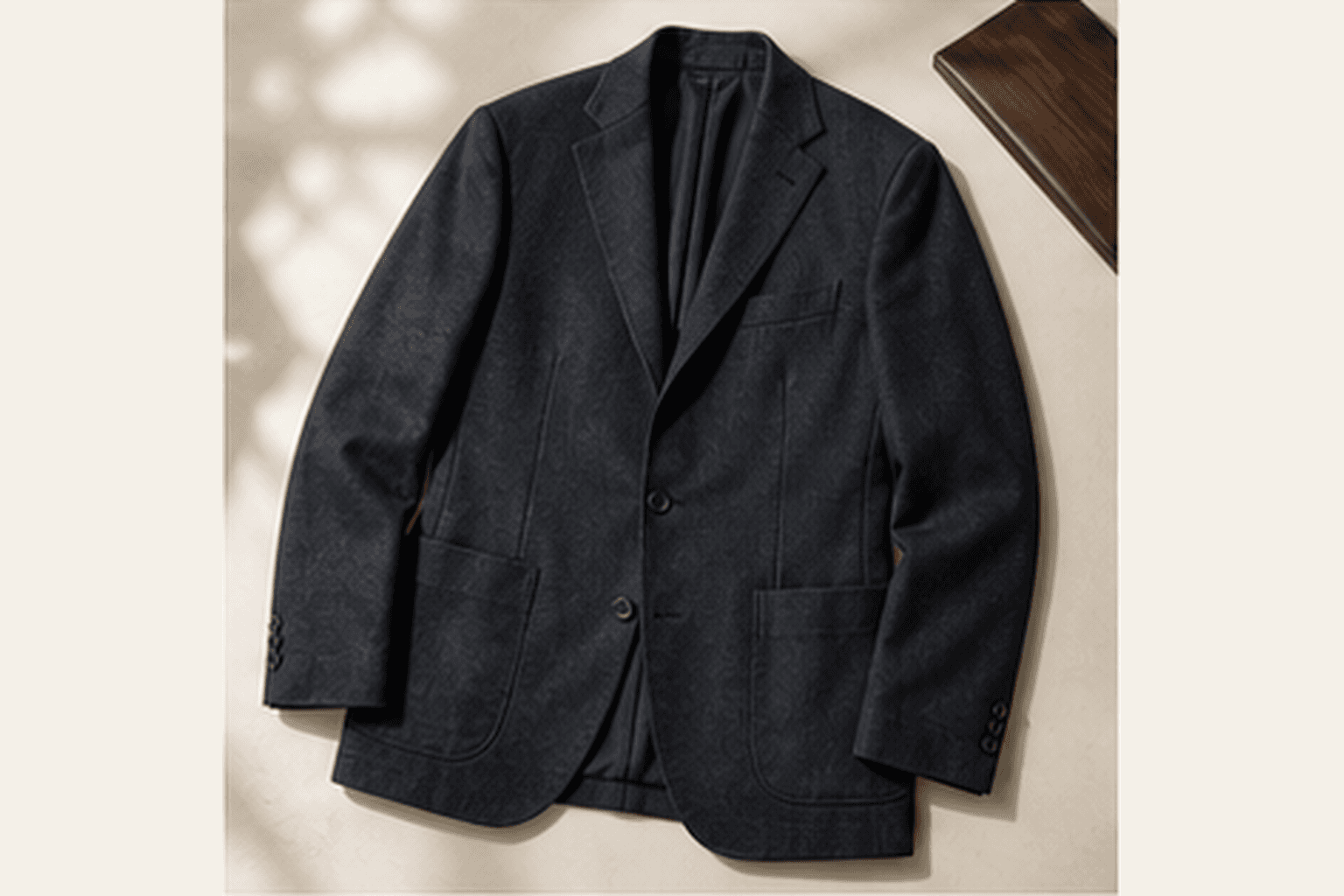 Soft charcoal unstructured blazer laid on a neutral office surface.