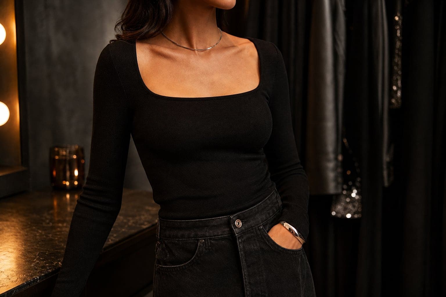 A black fitted top styled with dark night-out pieces in warm low light.